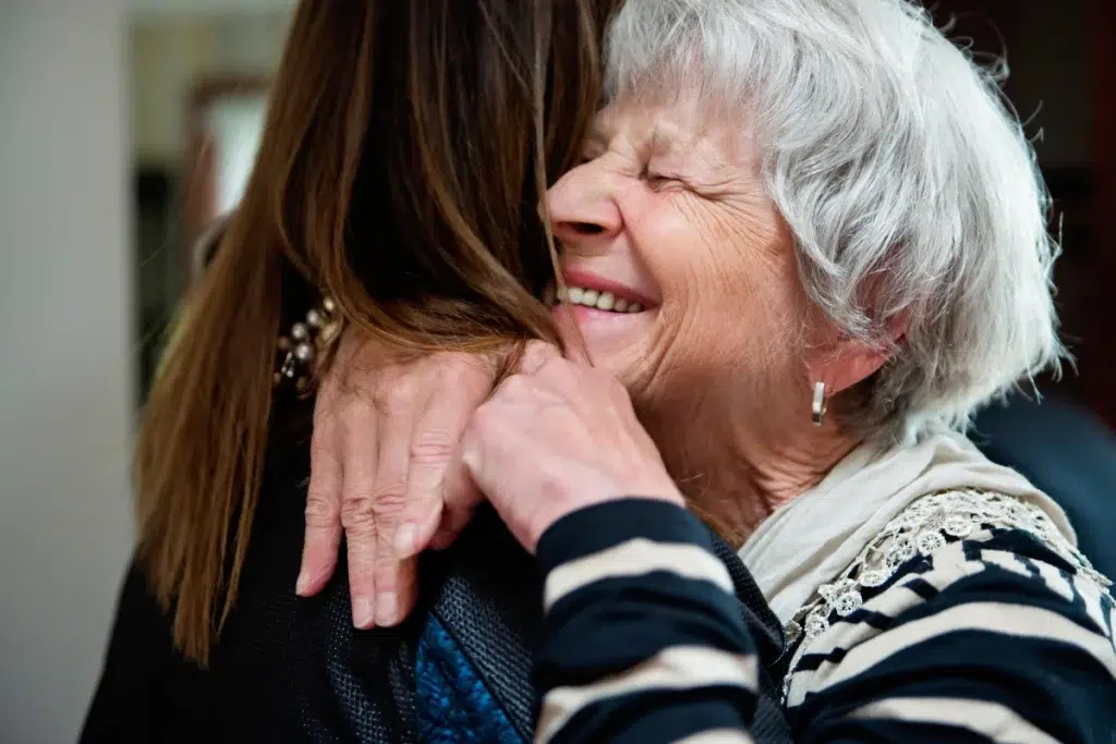 Un portrait chaleureux et lumineux d'un senior souriant accompagné de sa fille, illustrant la sérénité et le lien familial