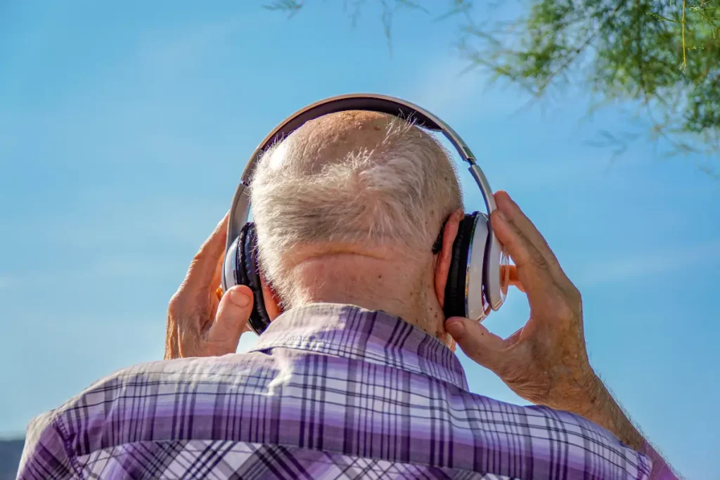 Un résident âgé souriant en écoutant de la musique avec un casque